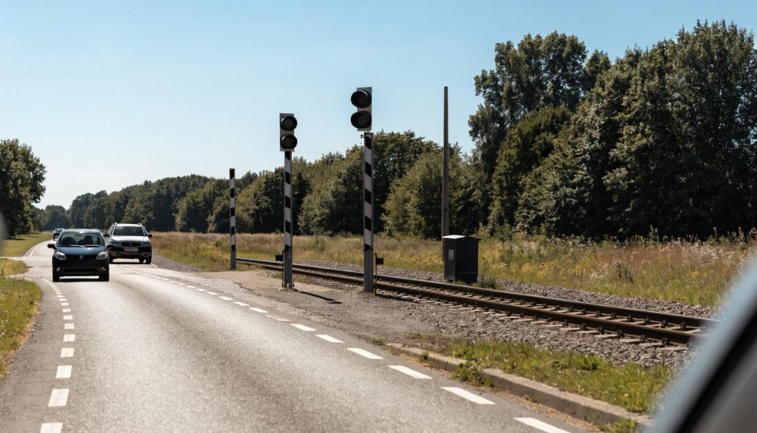 Ein Bahnübergang, an dem eine Straße mit Autos und eine Bahnstrecke aufeinandertreffen