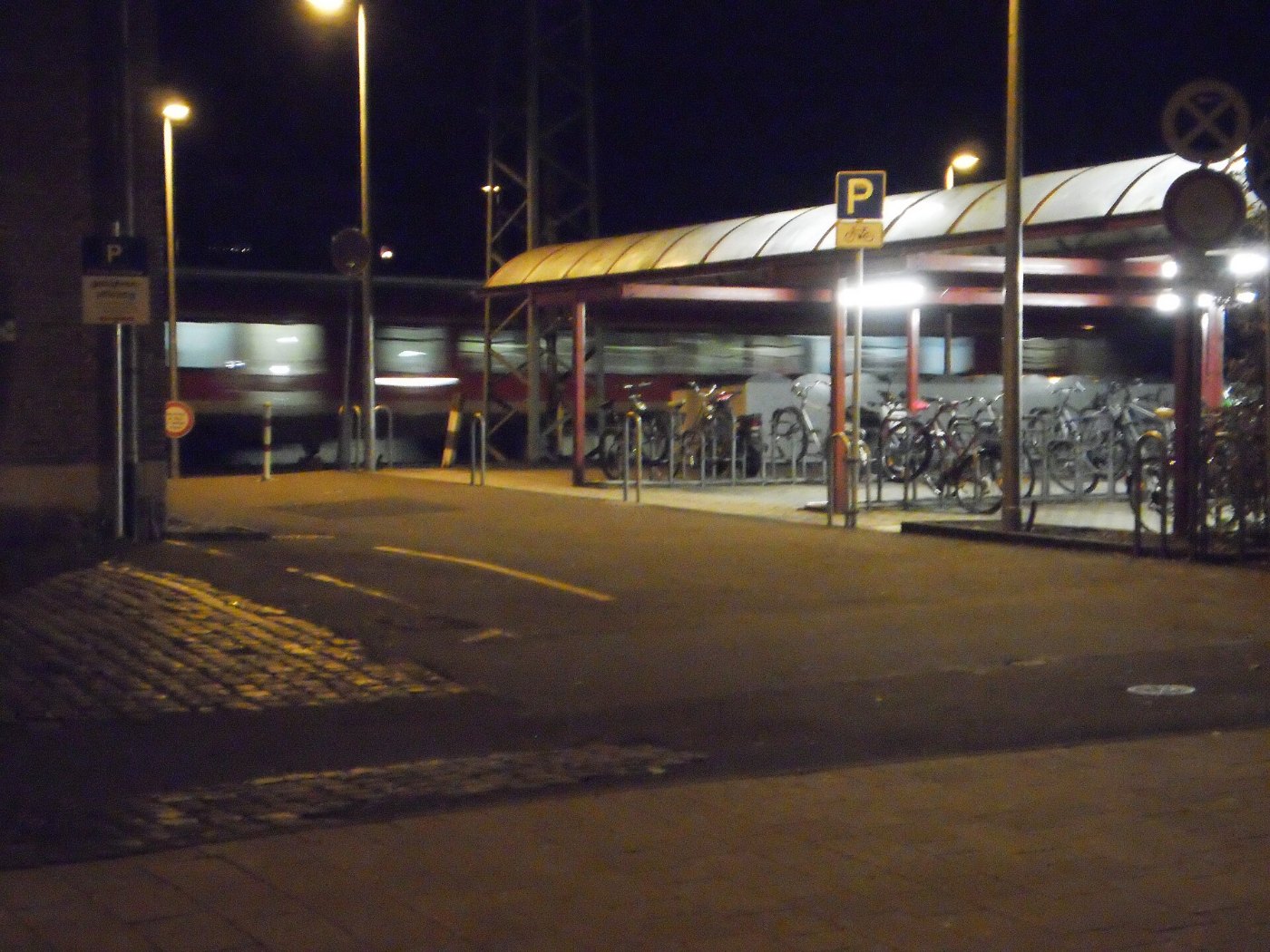 Beleuchtete Fahrradabstellanlage am Bahnhof Marburg mit fahrendem Zug 20