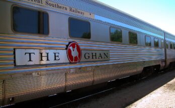 Side view of passenger car with livery of The Ghan train (Great Southern