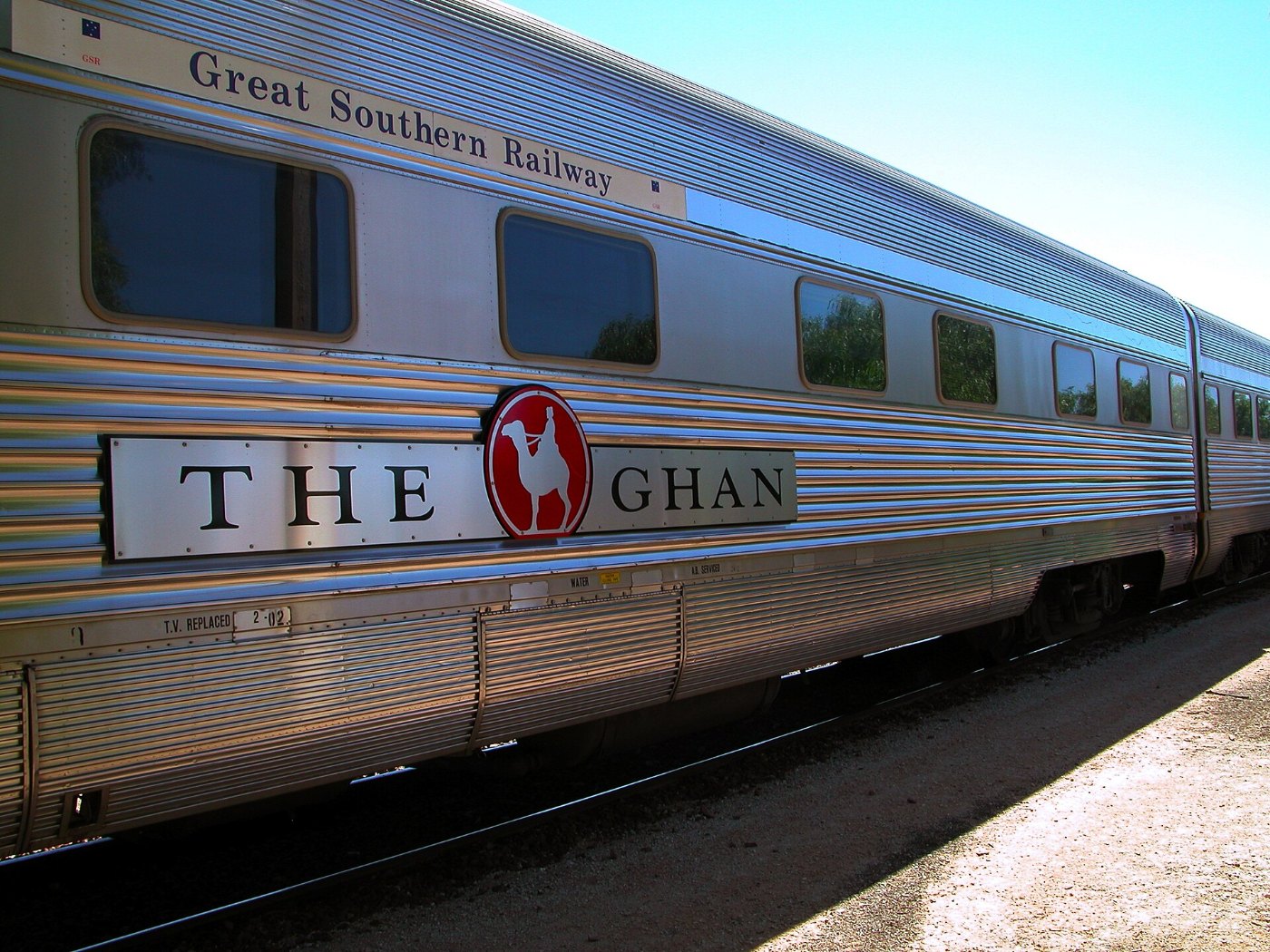 Side view of passenger car with livery of The Ghan train (Great Southern