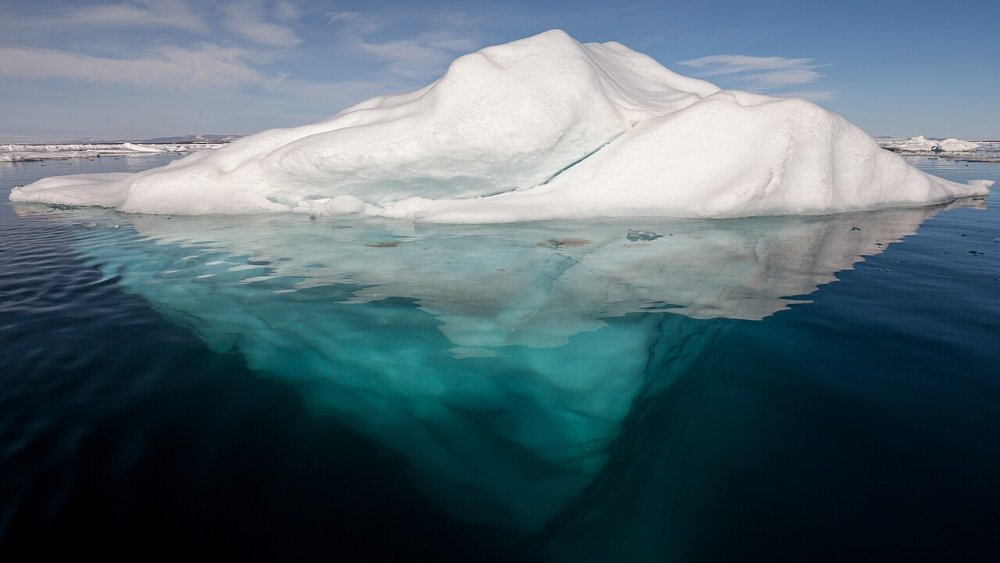Eisberg mit sichtbarer Unterseite im arktischen Wasser als Sinnbild fuer die Metapher