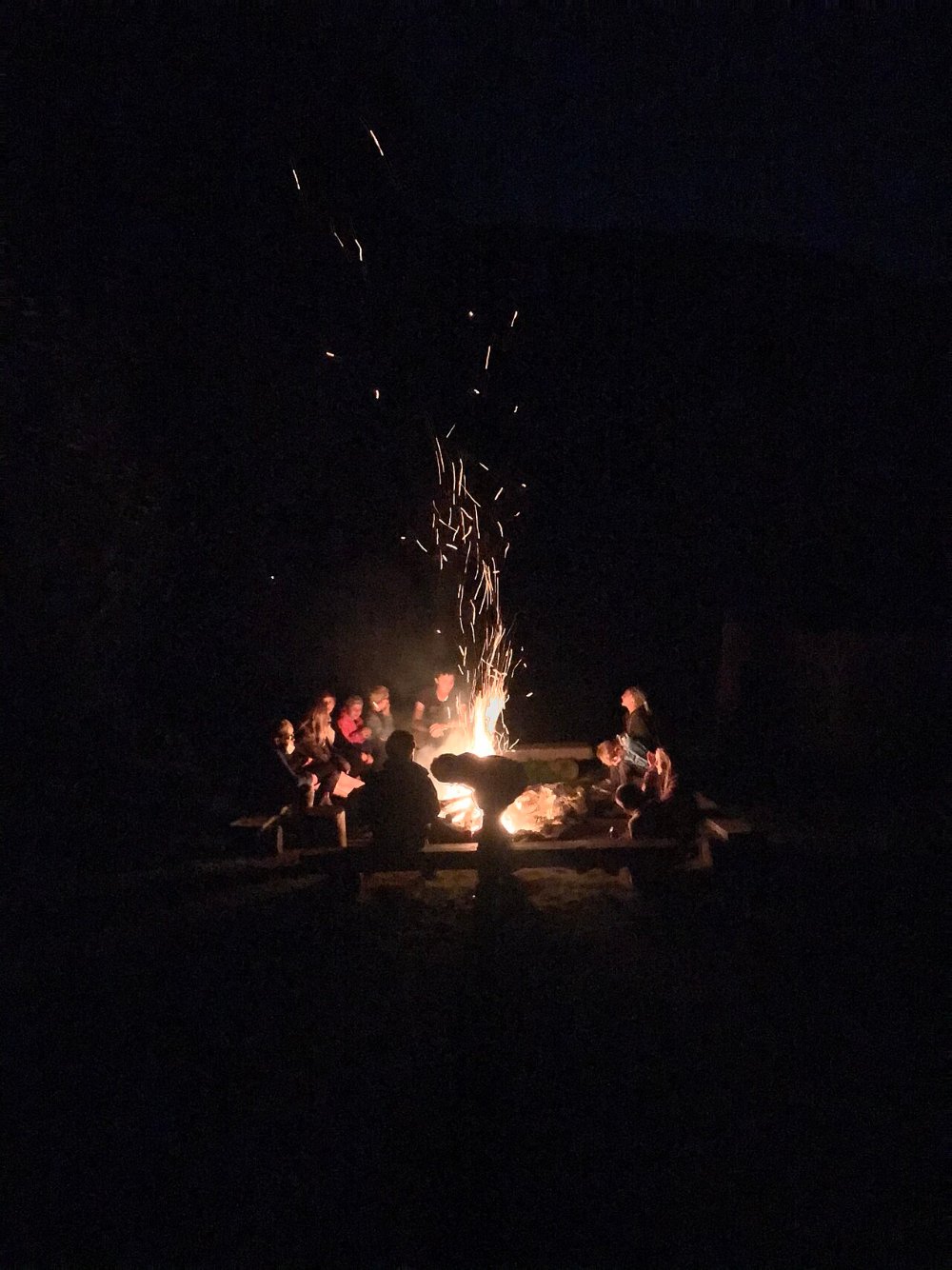 Menschen sitzen am Lagerfeuer und erzaehlen sich Geschichten