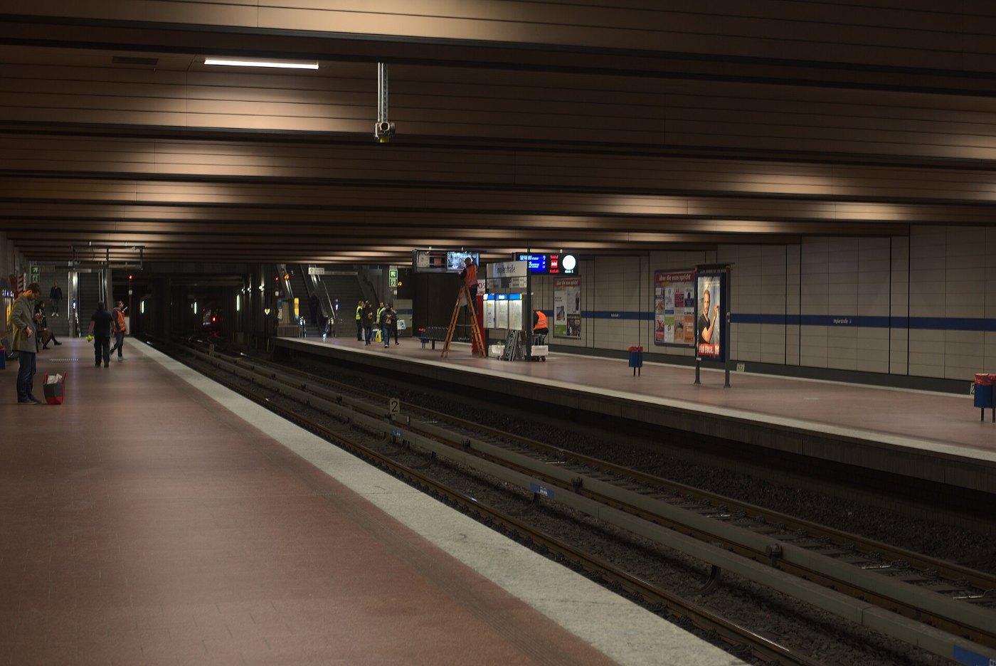 Reisende warten am Bahnsteig vor einer Anzeigetafel