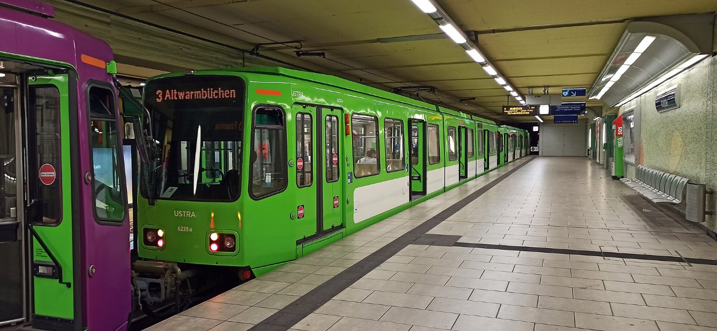 Reisende steigen am Bahnsteig zwischen zwei Zügen um