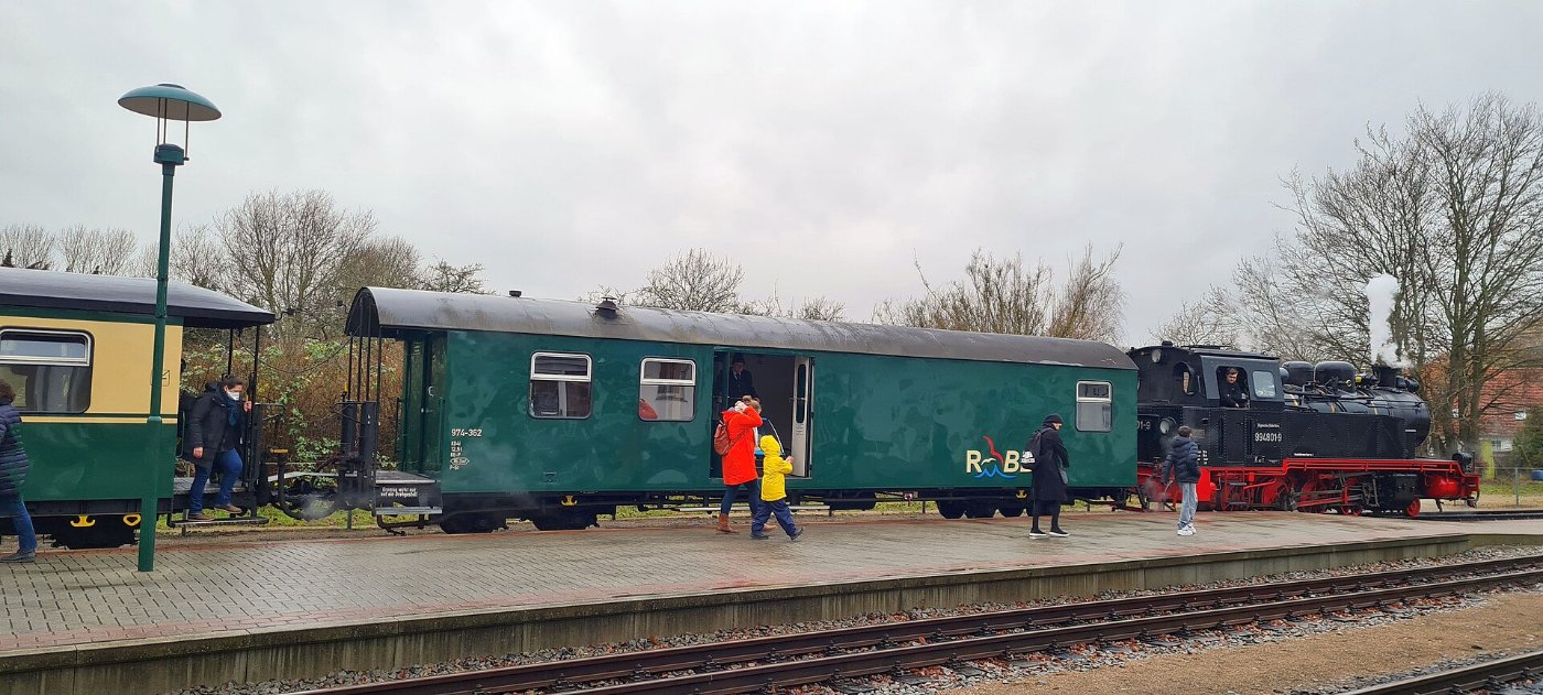 Reisende am Bahnsteig neben einem Zug